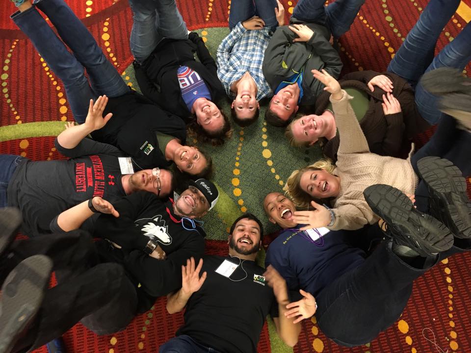 group of people laying on the floor with heads together creating a circle!