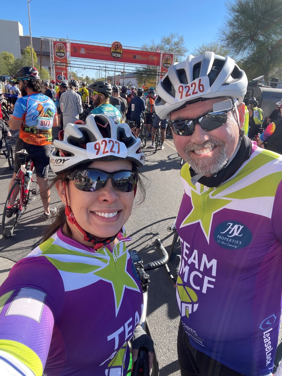 2 cyclists taking a selfie in front of a huge crowd of cyclists 