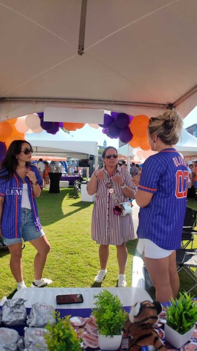 ApartmentsForClemson team members talking with a parent about off-campus housing at the Clemson Family Weekend tailgate