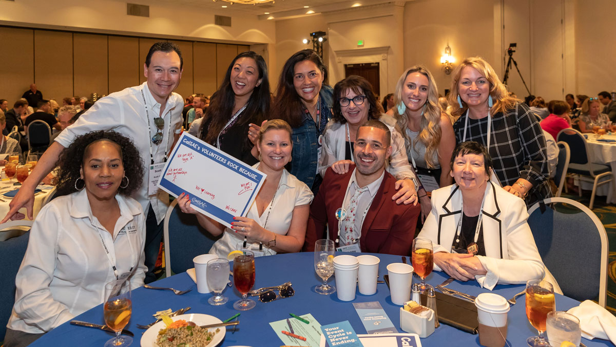 Group gathered a luncheon holding up sign