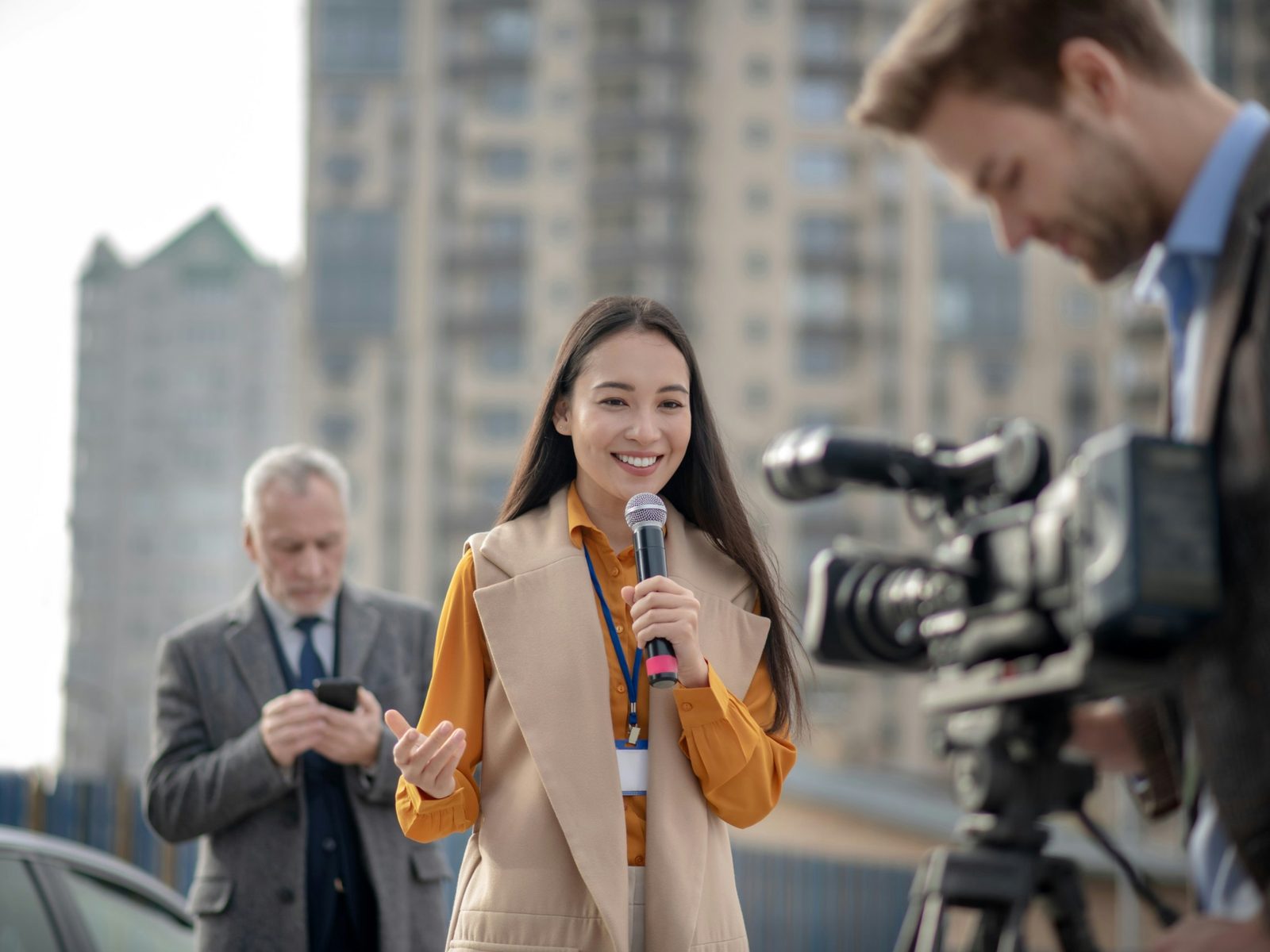 A reporter speaks into a microphone as a camera operator films