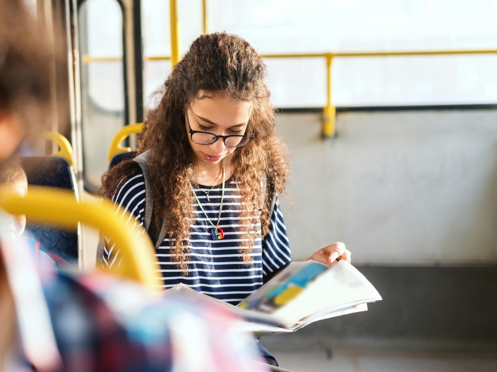 A young woman reads a magazine on a bus