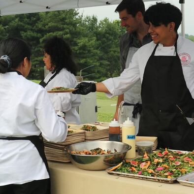 Student Christopher Ramirez, Julissa Negron and Daisy Galicia-Lucero  ​help plate the first course prepared by Chef Clark Neugold. 