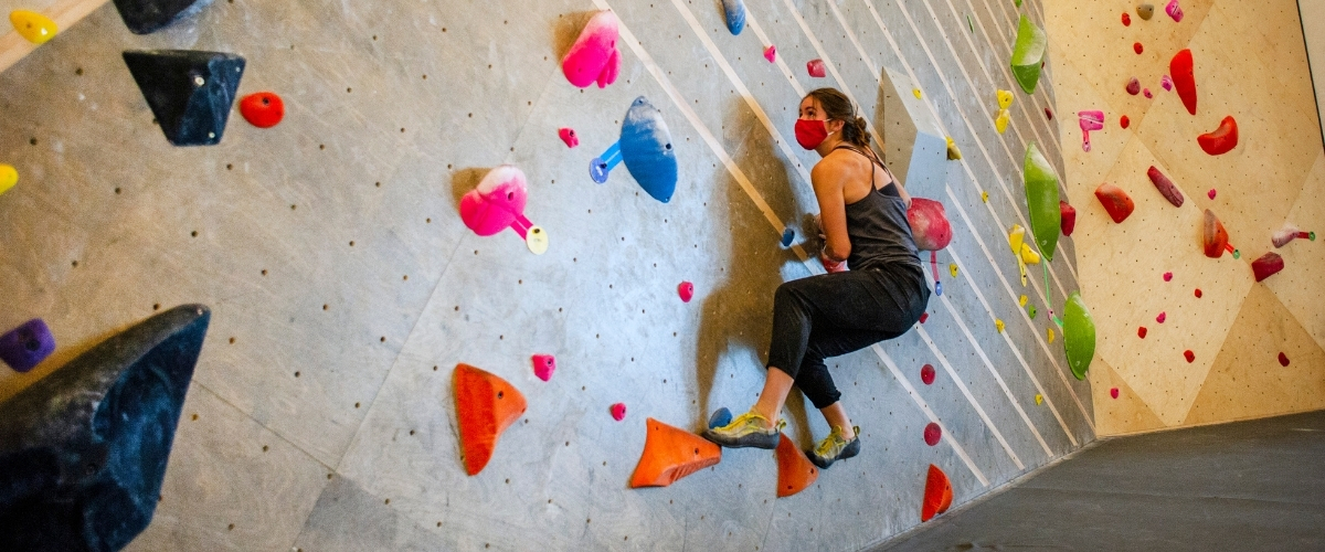 Woman climbing indoors in mask