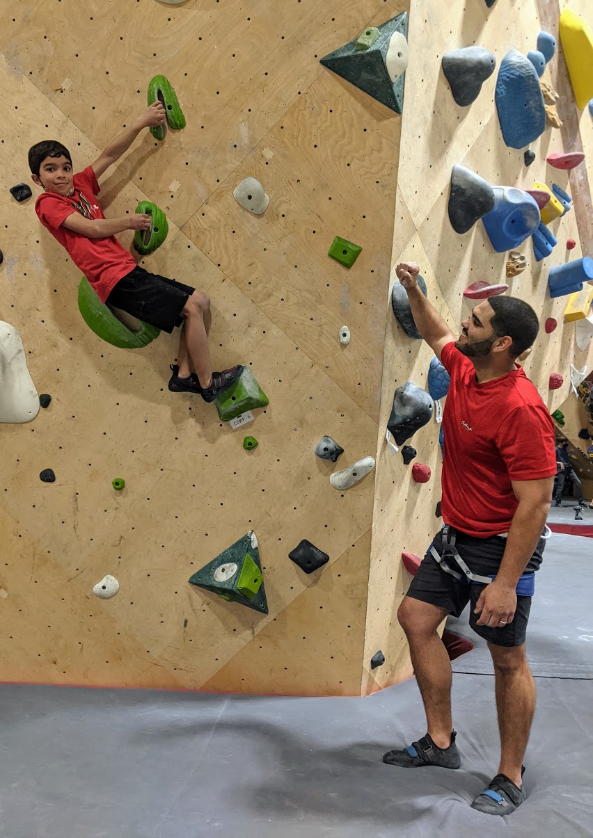 Child rock climbing next to parent