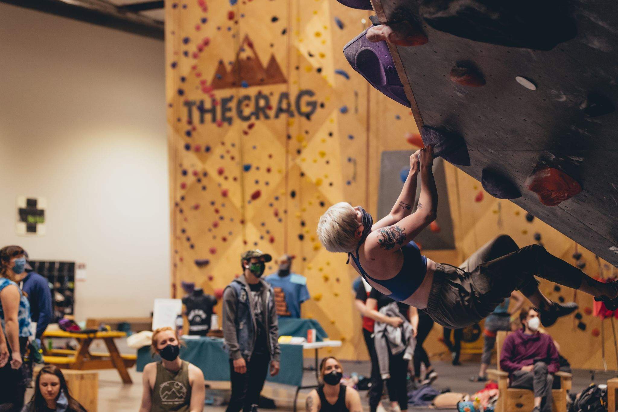 Woman rock climbing inside wearing mask