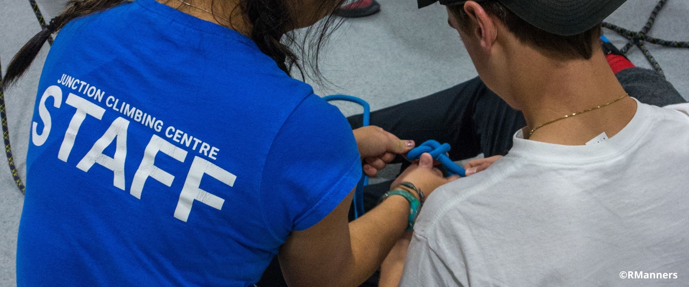 Indoor climbing gym employee helping member