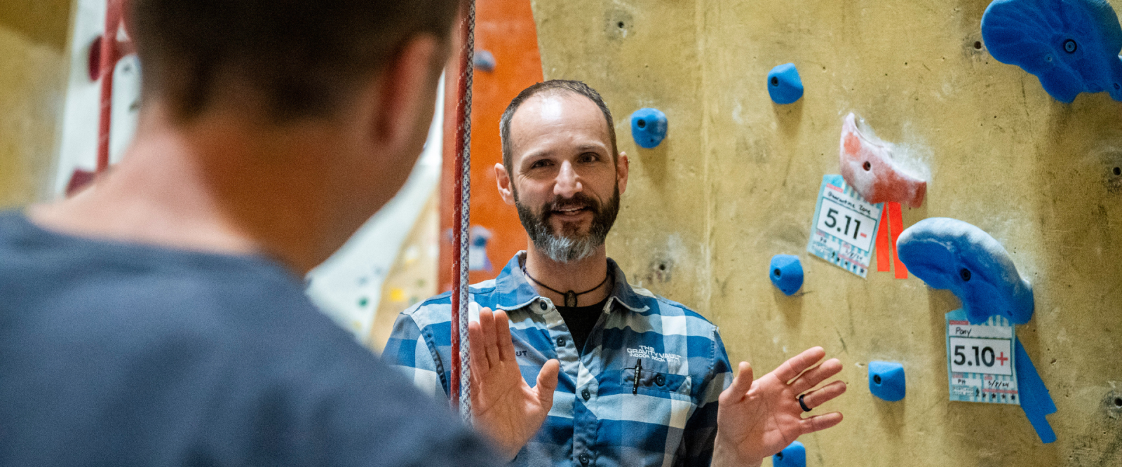 Two people talking inside an indoor climbing gym