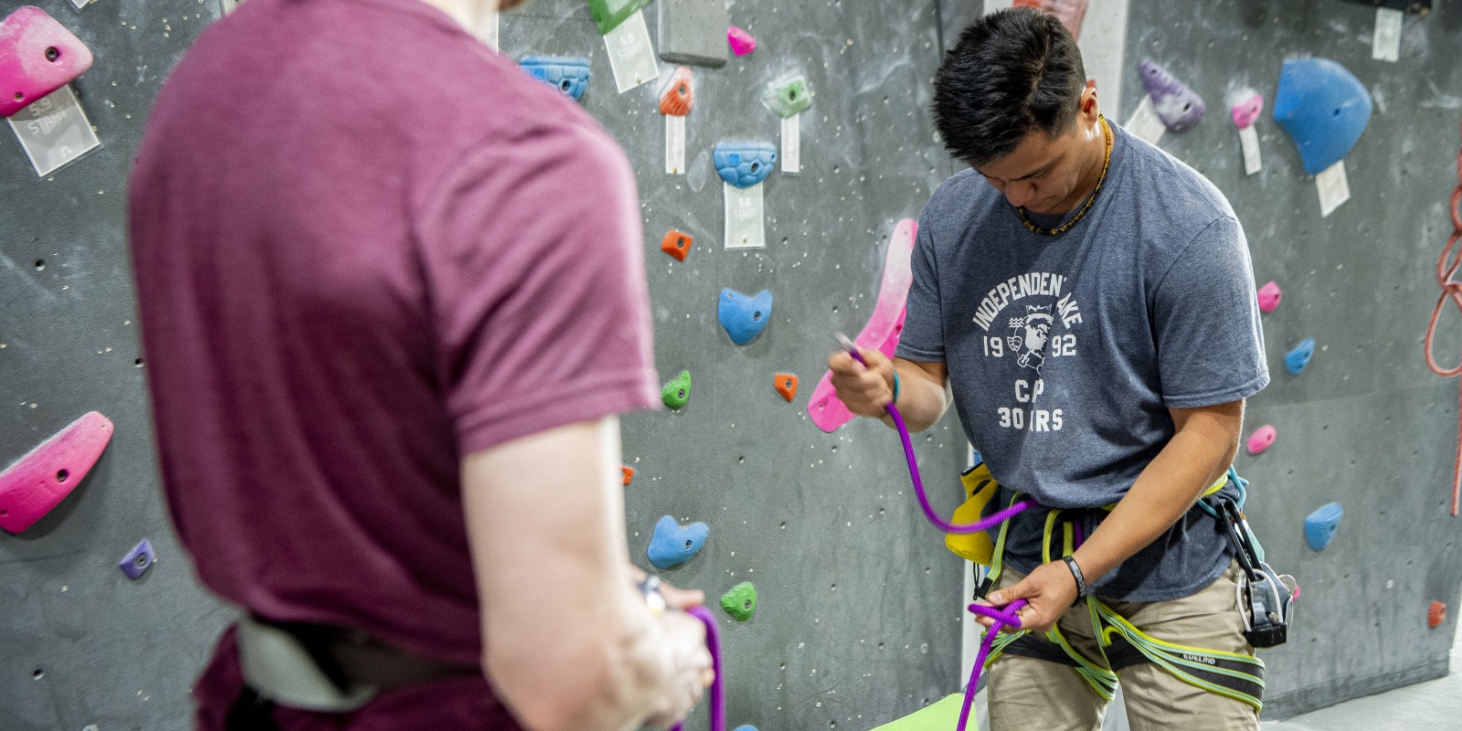 A person tieing into a harness in an indoor climbing gym