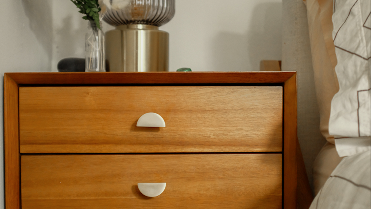 Hapny Half Moon knobs in Satin Brass installed on a wood nighstand