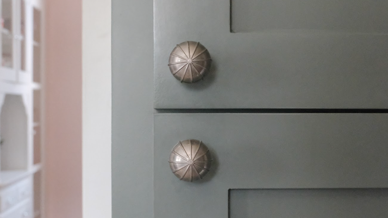 Hapny Sunburst knobs in Satin Nickel installed on blue kitchen cabinets