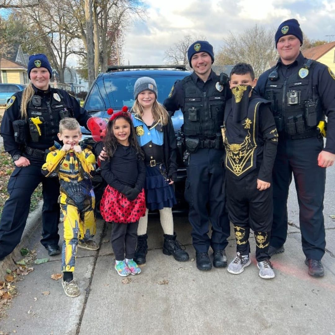 Cops and kids in front of squad car.