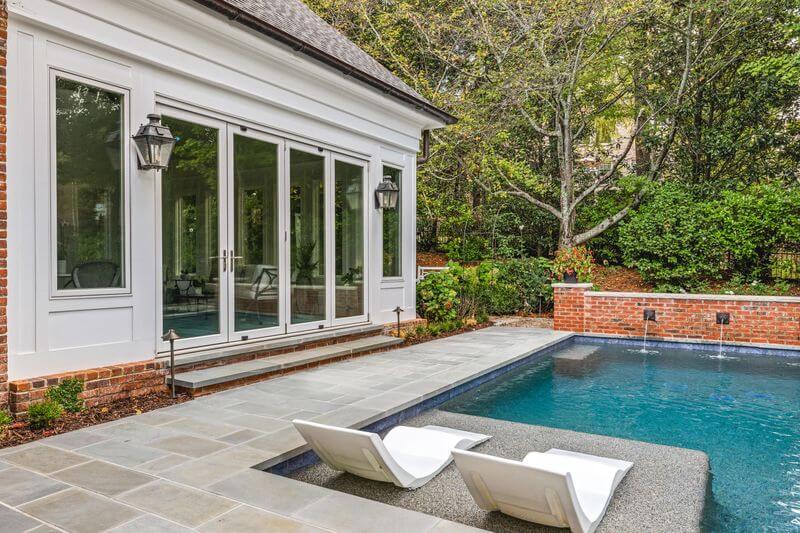 A pool and a house with a deck chairAI-generated content may be incorrect.