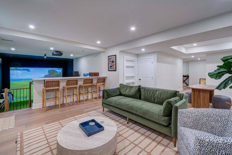 A living room with a green couch and a bar stools