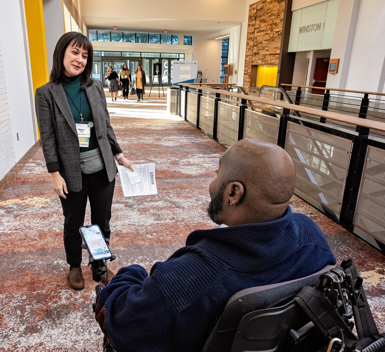Megan and LaMondre talk before the conference begins. The photo is taken from behind LaMondre and we see him looking towards Megan and Megan smiling.