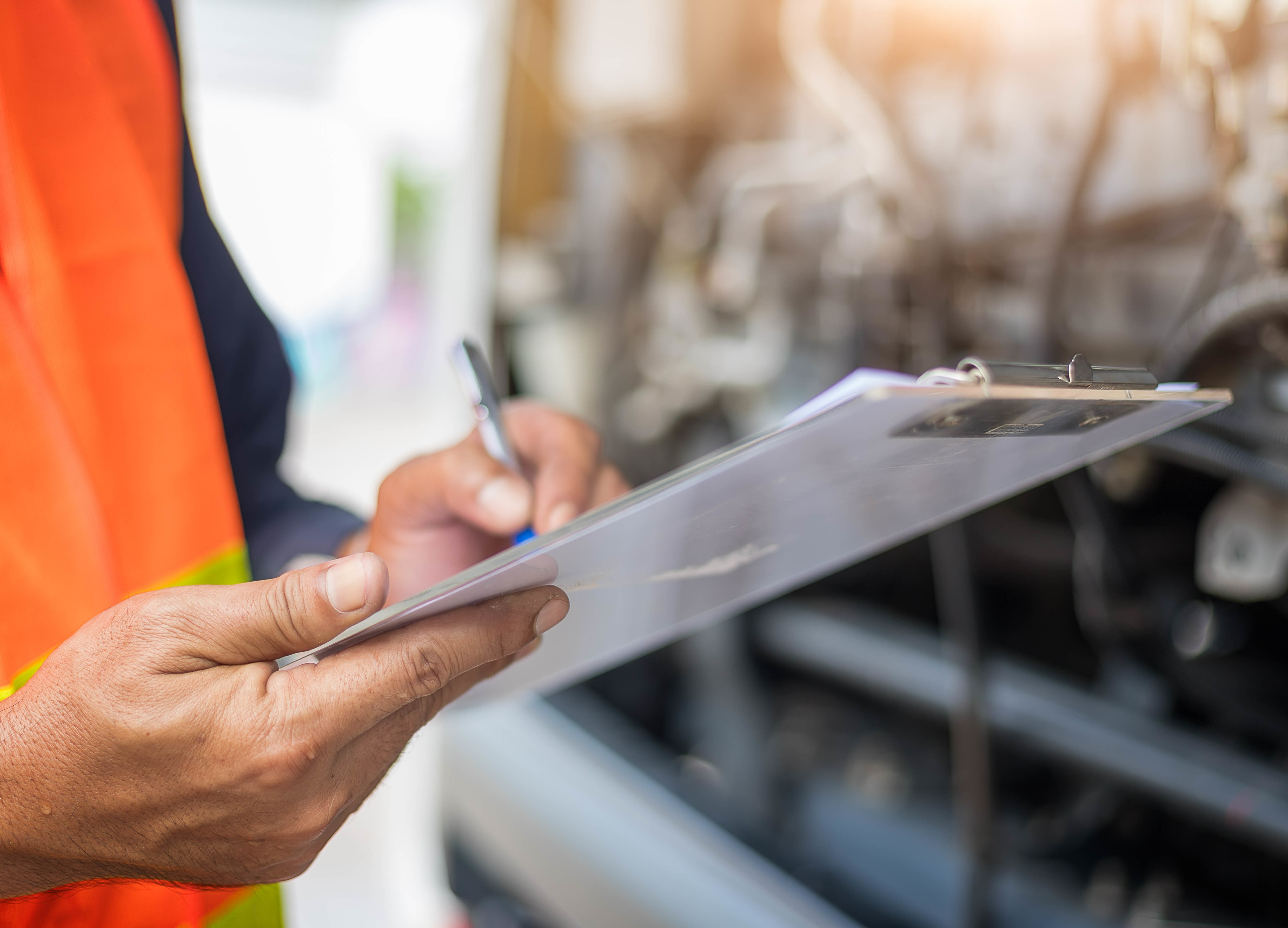 worker writing on clipboard in factory setting