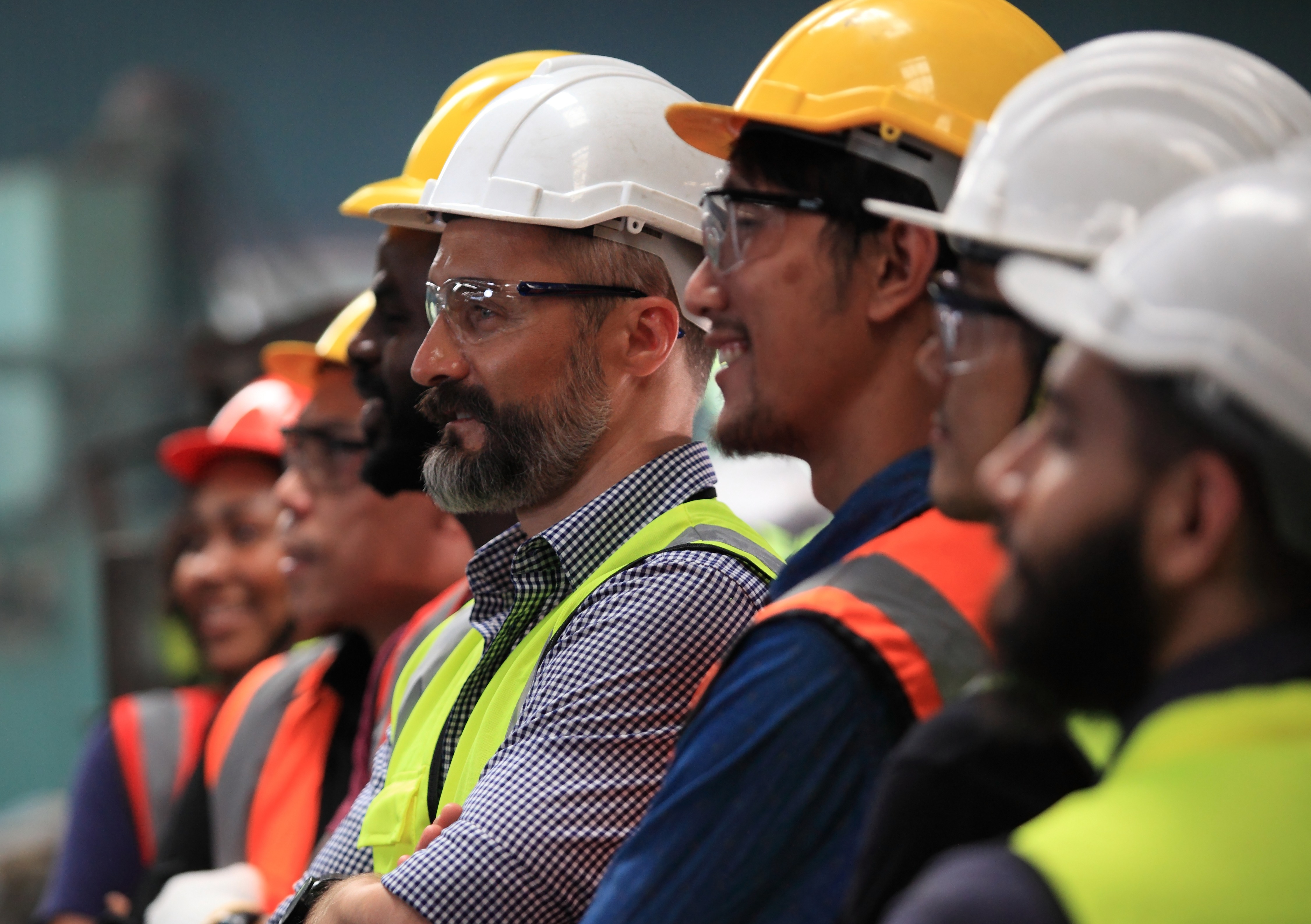 Manufacturing workers with PPE smiling and looking at something out of the frame