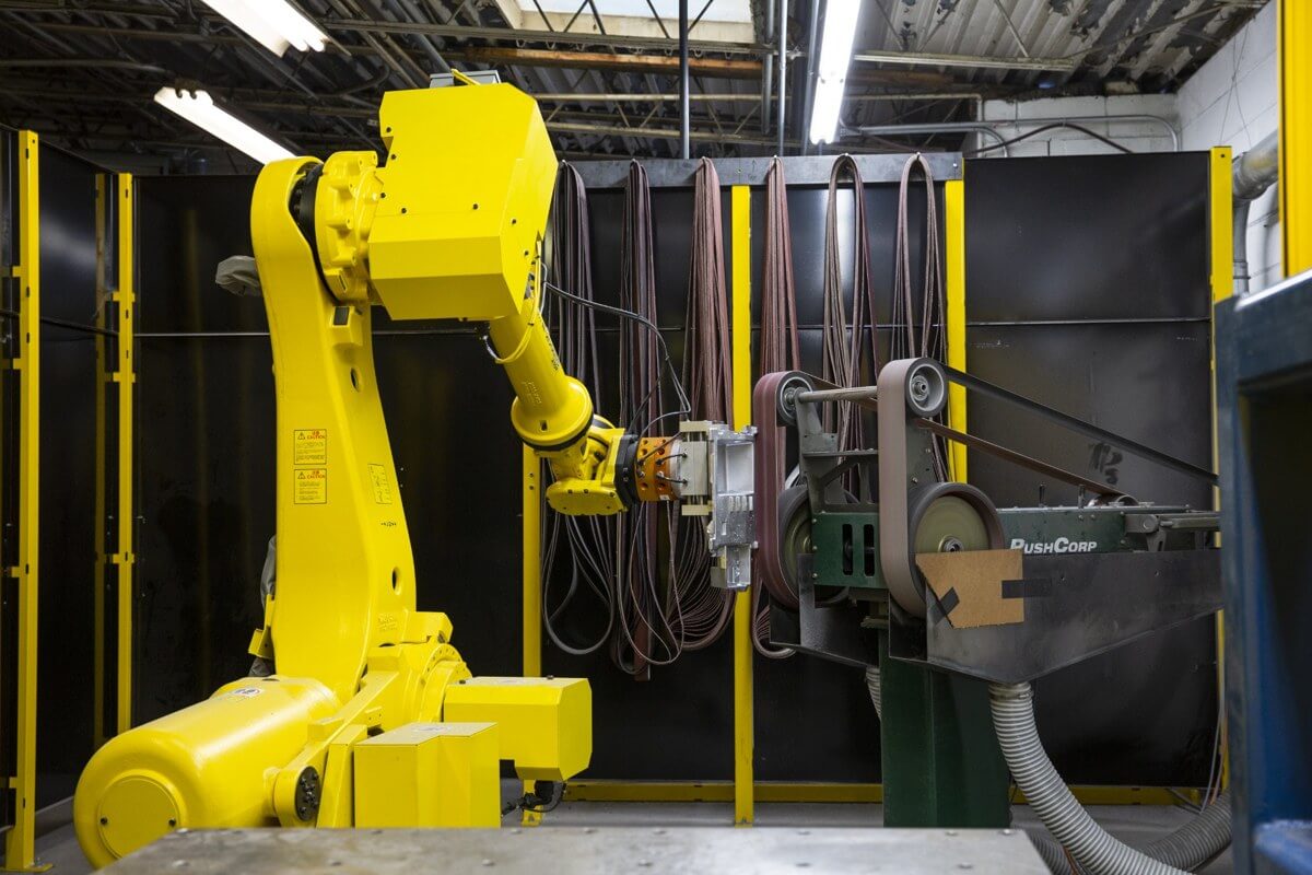 Yellow industrial robot beside manufacturing equipment at Batesville Products