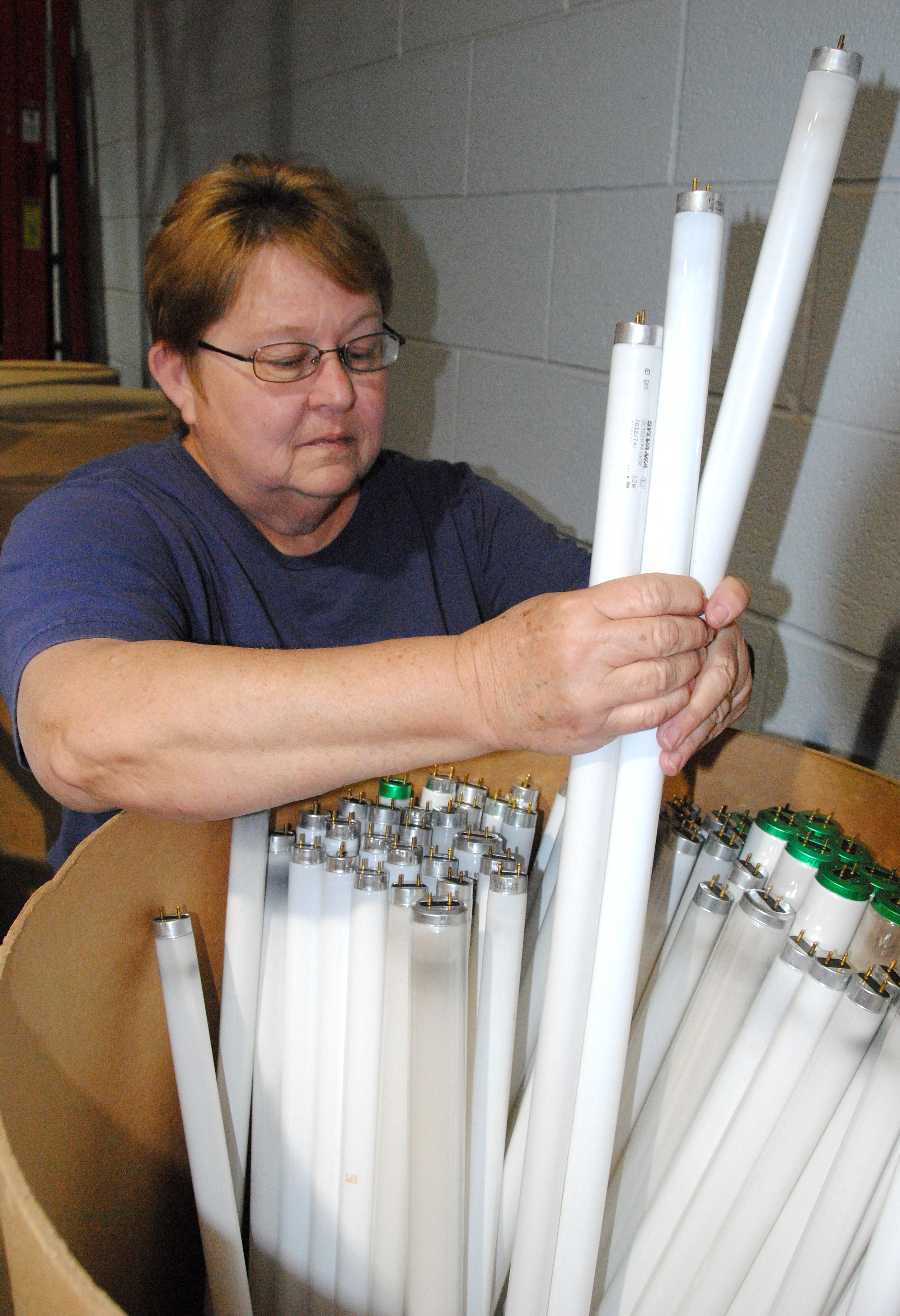 woman handling long fluorescent bulbs in a box