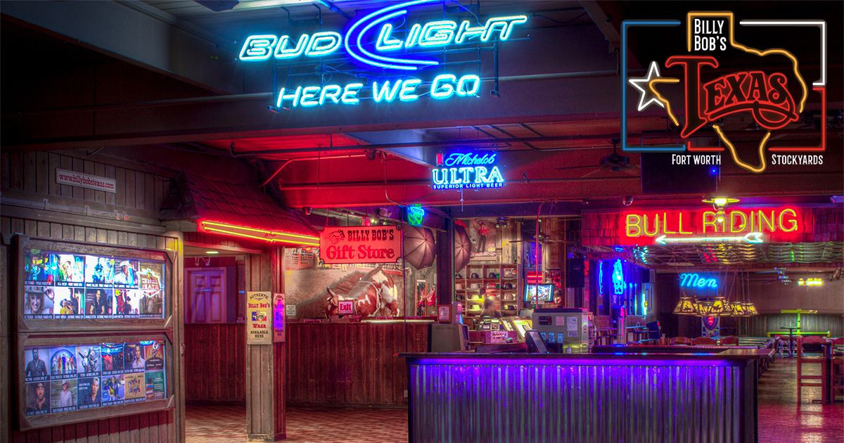 Photograph of the inside of Billy Bob's Texas with a neon Bud Light sign and the Billy Bob's logo