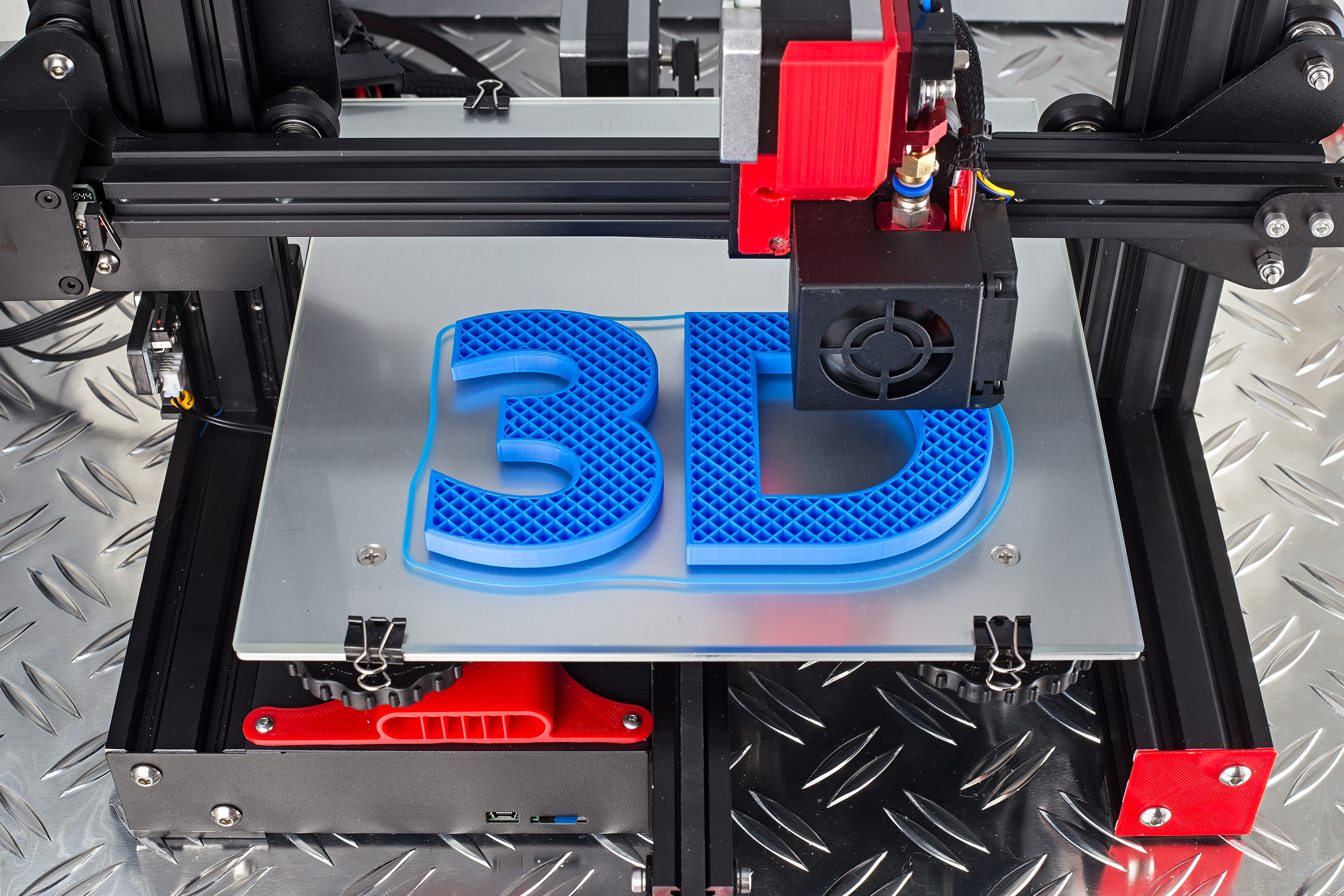 3D printer printing blue block letters "3D"