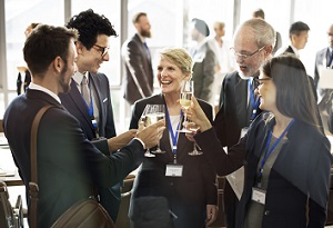 Professionals smiling and talking while holding drinks