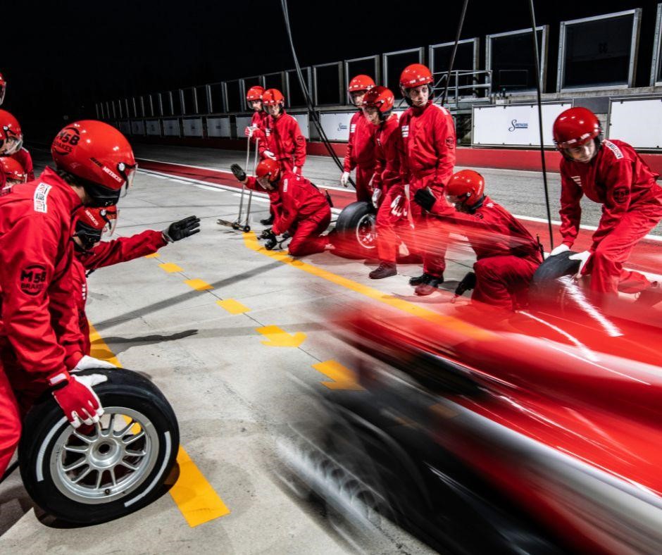 motion shot of red race car and pit crew in action