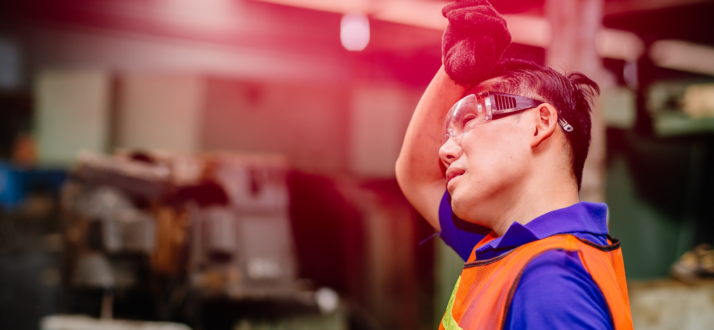 Factory worker wiping sweat from his brow