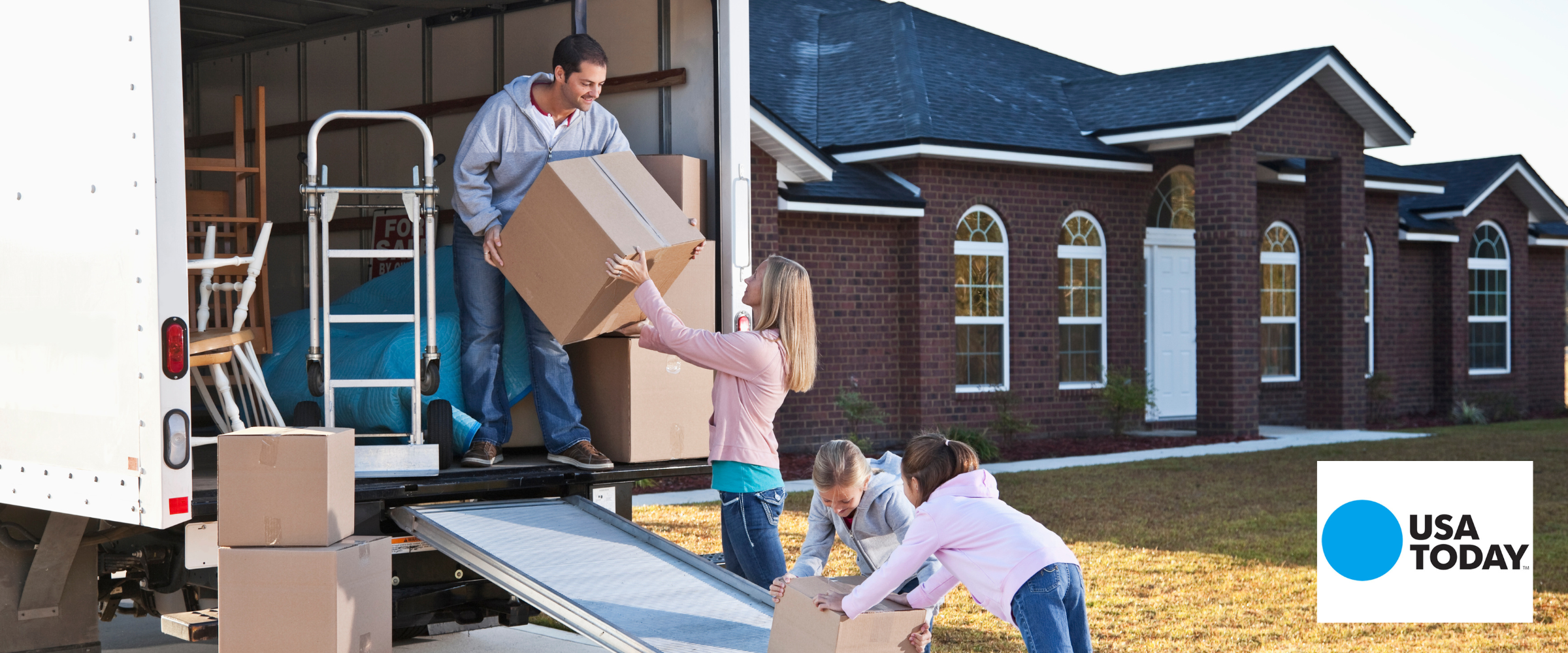 People moving boxes off a moving truck. USA Today's logo is in the corner.