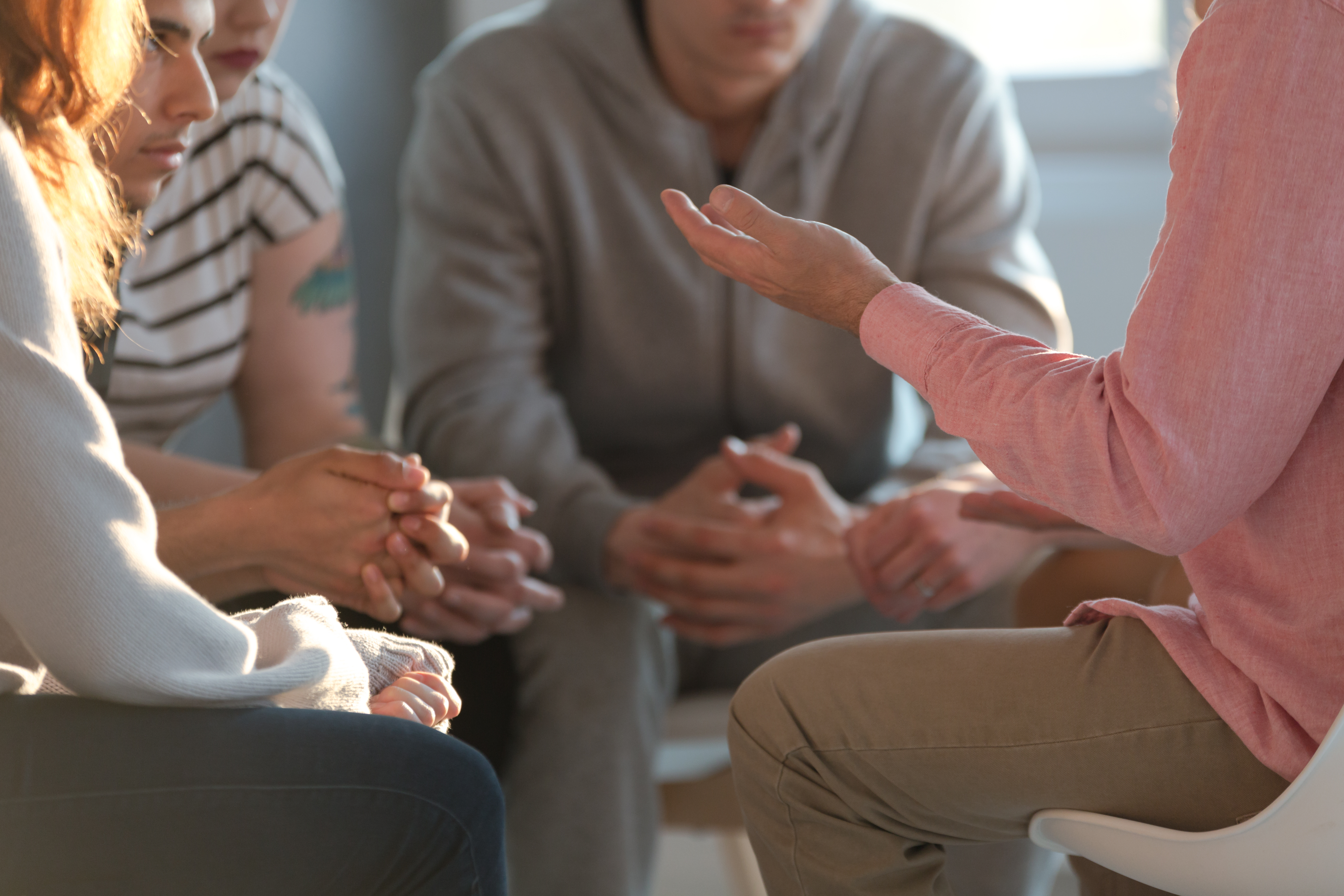 a group of therapy clients sit in a circle and discuss