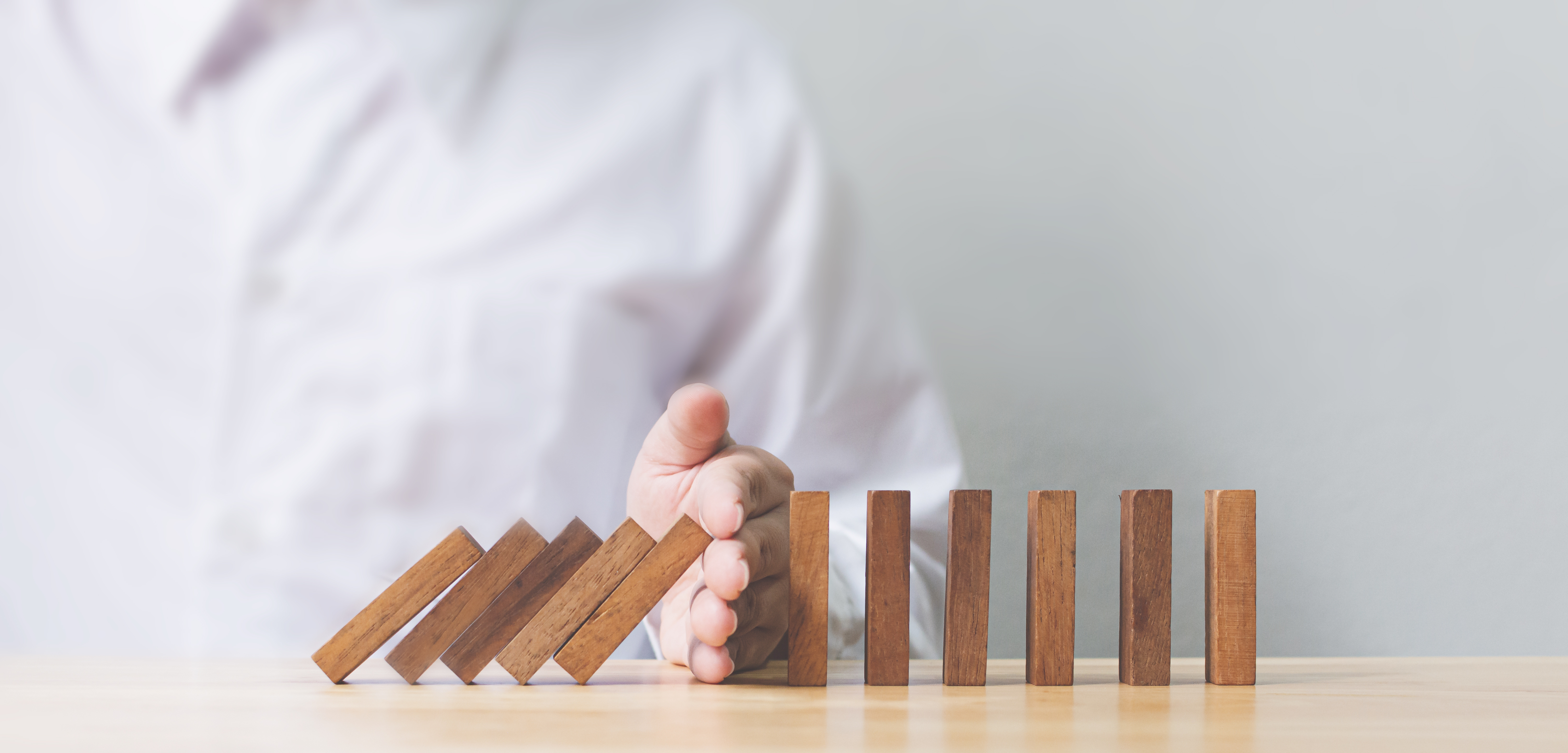 a hand keeps a row of upright jenga blocks from falling