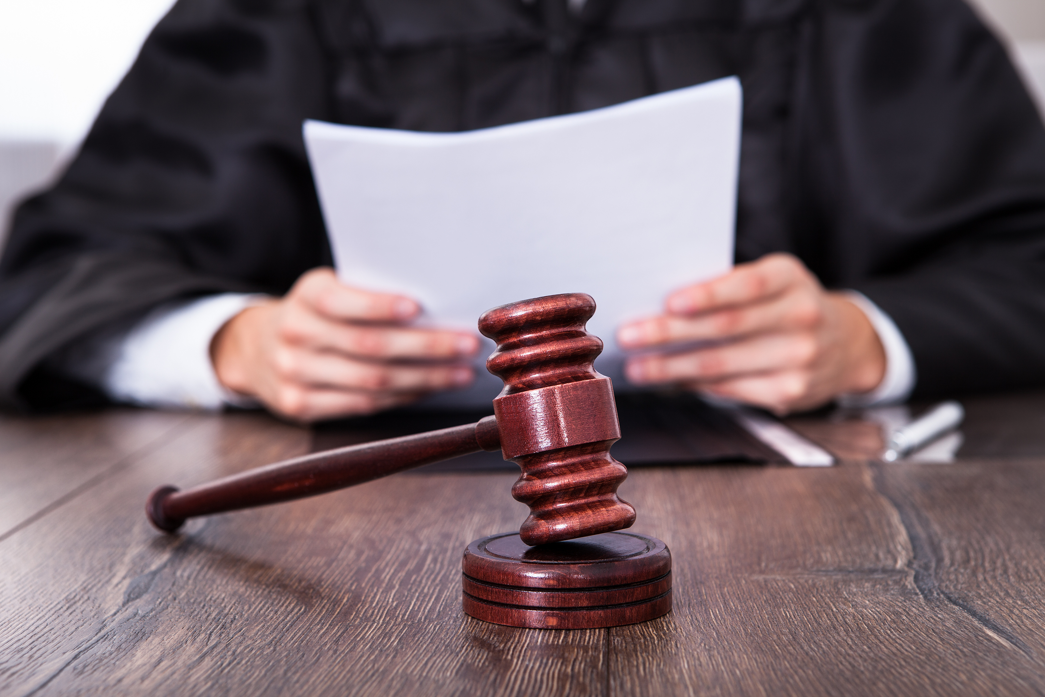 a judge reviews a document with a gavel in the foreground