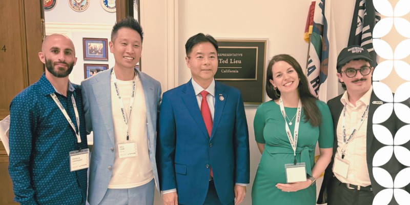 PBFA members stand in a row indoors next to an official wall sign that reads "REPRESENTATIVE Ted Lieu, California". They are wearing conference name tags, and a white geometric pattern frames the right border.