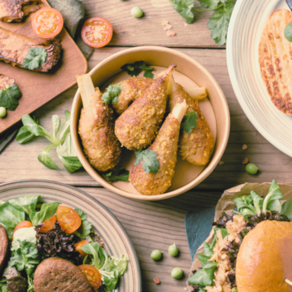 Photo of plant-based chicken wings on a table surrounded by complementary foods.
