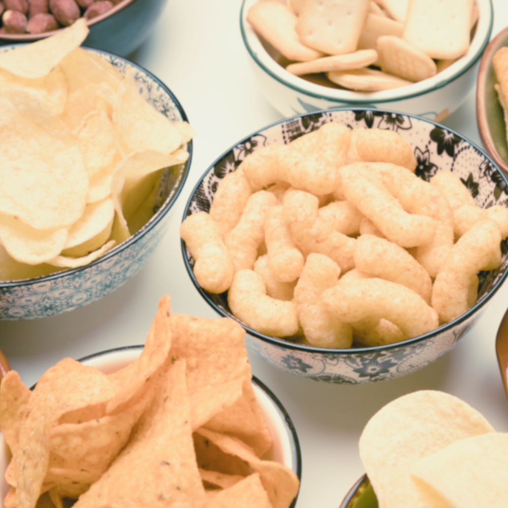 Several bowls of plant-based snacks including chips and mac n cheese.