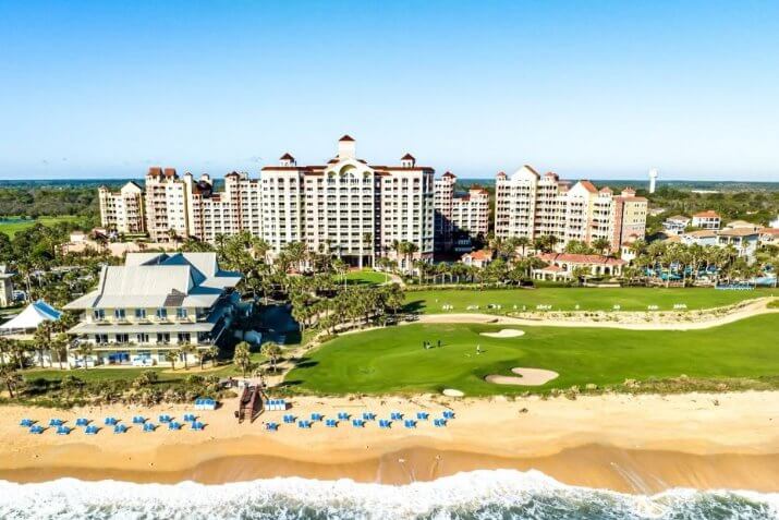 A beach with a large building and a golf courseAI-generated content may be incorrect.