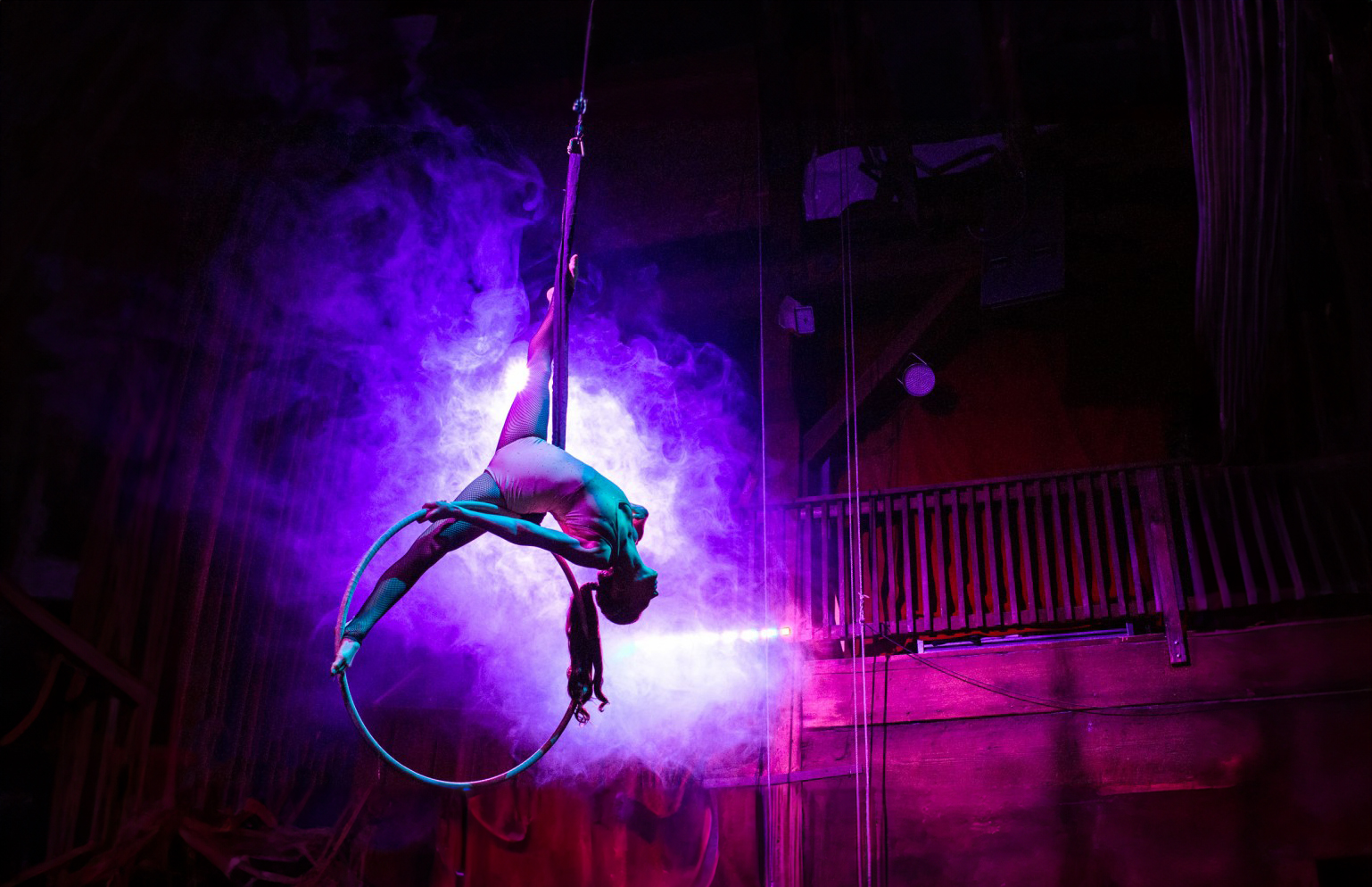 A woman is performing aerial acrobatics in a dark room