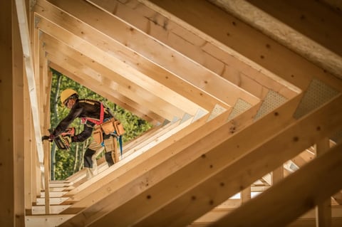 Man working on roof truss with nail gun