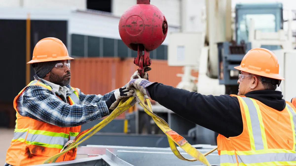 Two construction workers loading a crane.