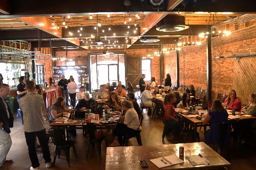 A group of people sitting at tables in a restaurantAI-generated content may be incorrect.