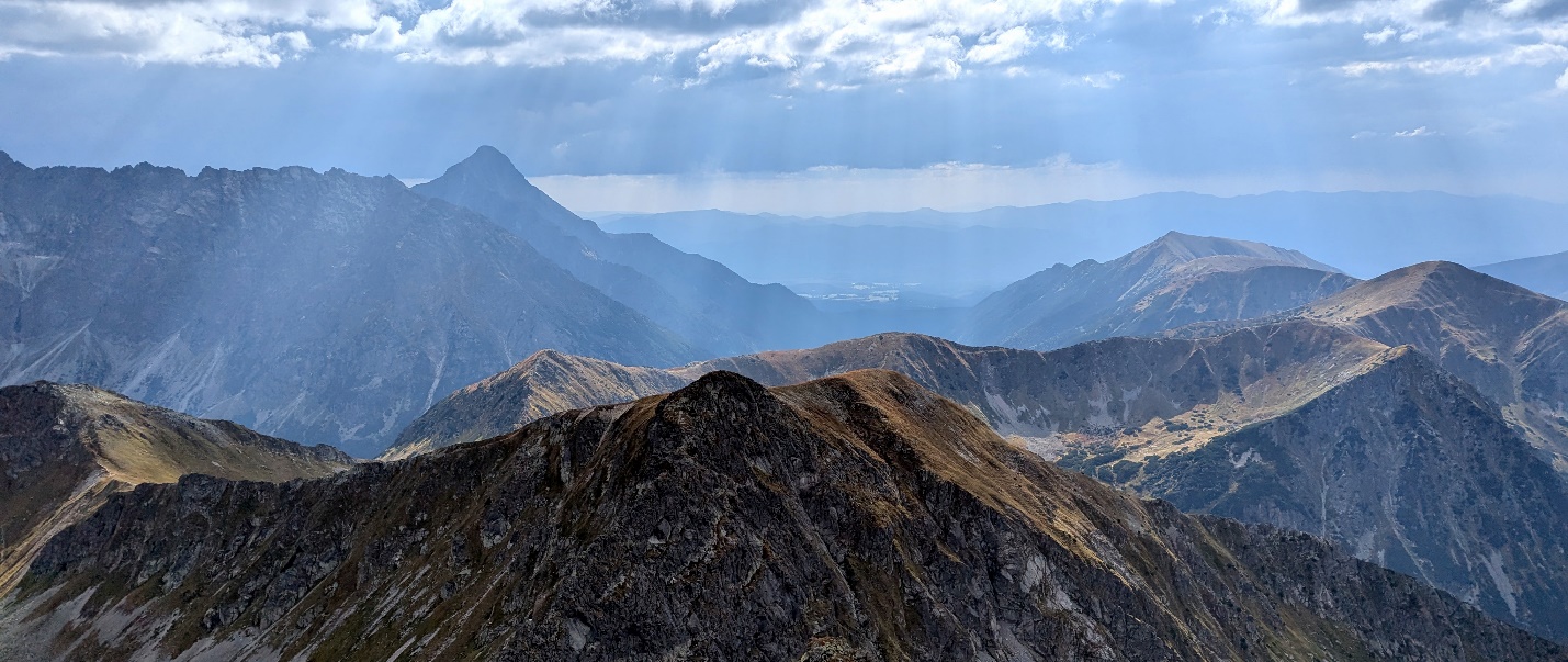 A mountain range with clouds in the skyDescription automatically generated