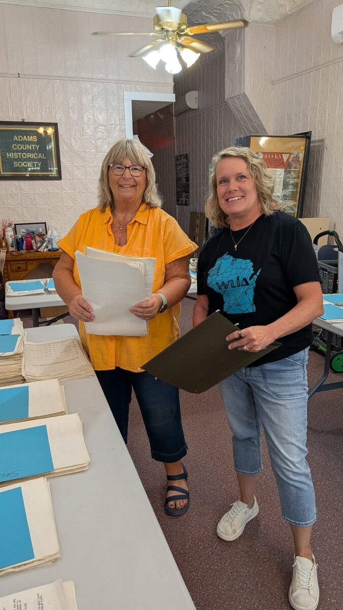 Jodi Helgeson and Kelly Felton smile for the camera while volunteering at the Adams County Historical Society