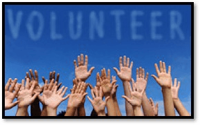 Raised hands in front of a sky with clouds forming the word "volunteer" in capital letters.