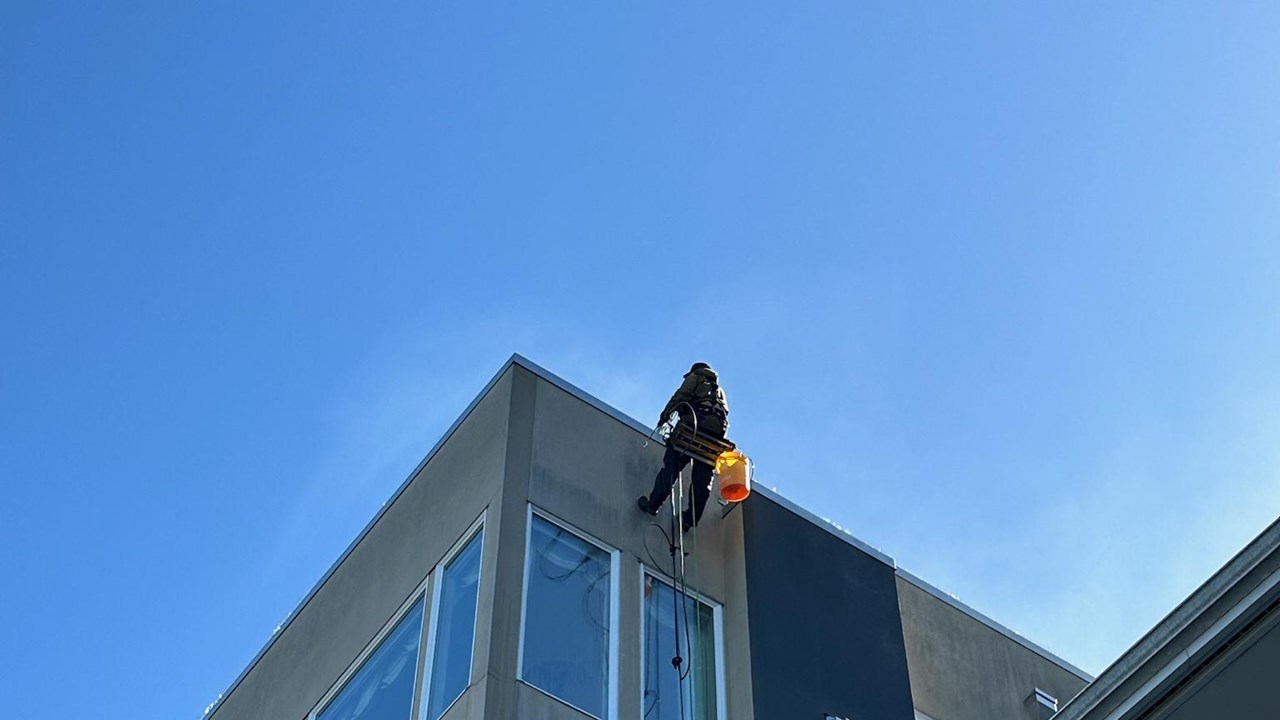 Starting on the corner of a stucco building cleaning.